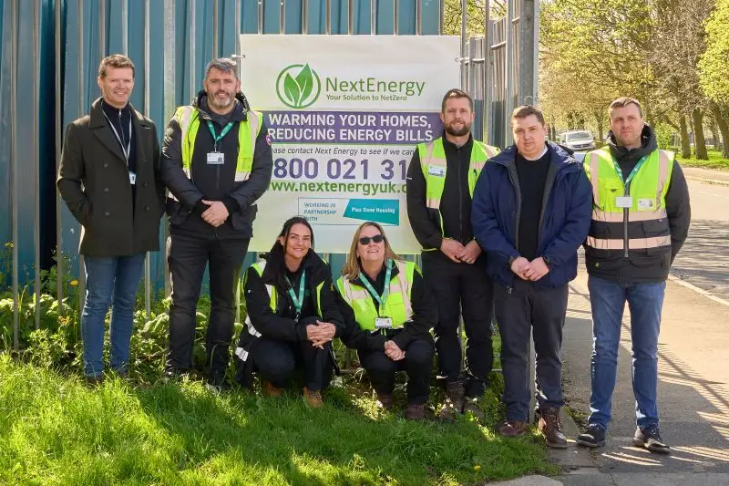 Next Energy team in front of promotional banner