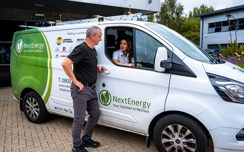 Man standing at door of a next energy van with female in the drivers seat.