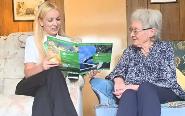 Next Energy staff member sat talking with elderly lady.